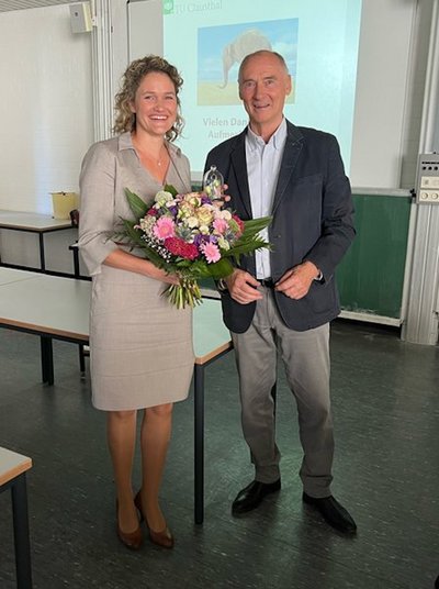 Person mit Blumenstrauß steht neben einer anderen Person 