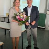 Person mit Blumenstrauß steht neben einer anderen Person 