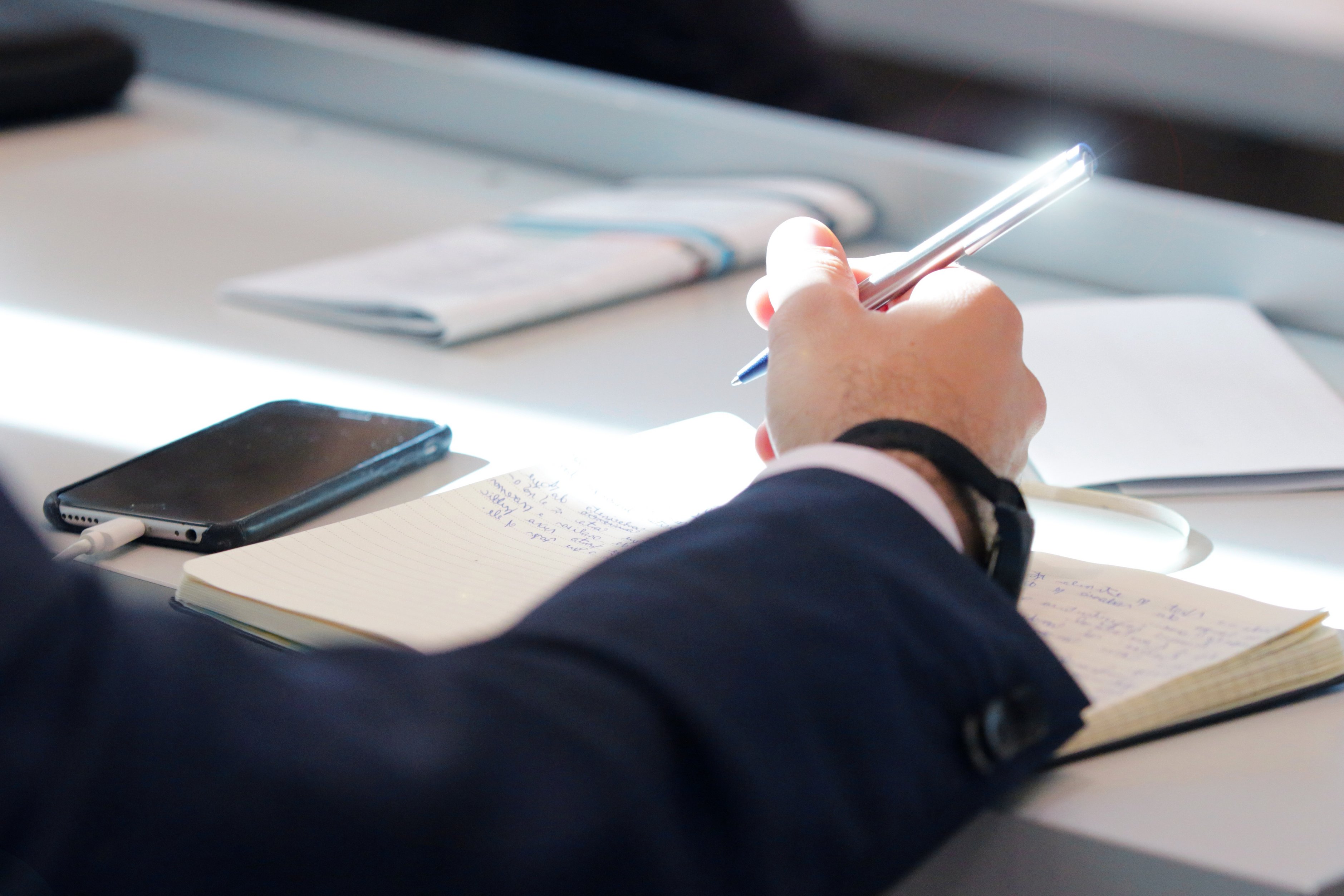 Hand hält einen Stift und schreibt auf ein Papier