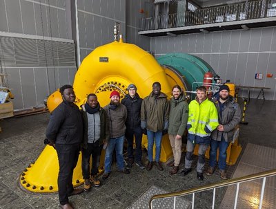 Besucher einer Exkursion stehen neben einer Francisturbine im Wasserkraftwerk Romkerhalle