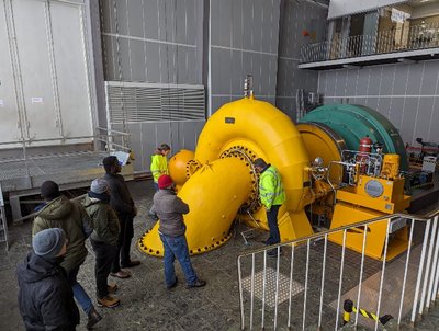 Besucher einer Exkursion stehen neben einer Francisturbine im Wasserkraftwerk Romkerhalle